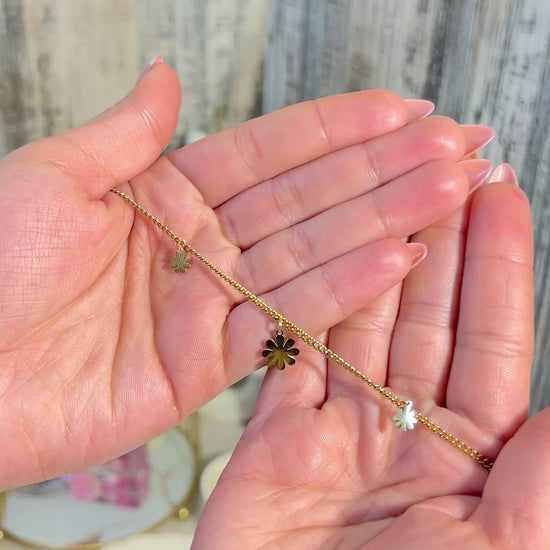 Waterproof Charm Bracelet - Delicate Gold Chain with Flower Charms held in hands, showcasing its elegance and charm.