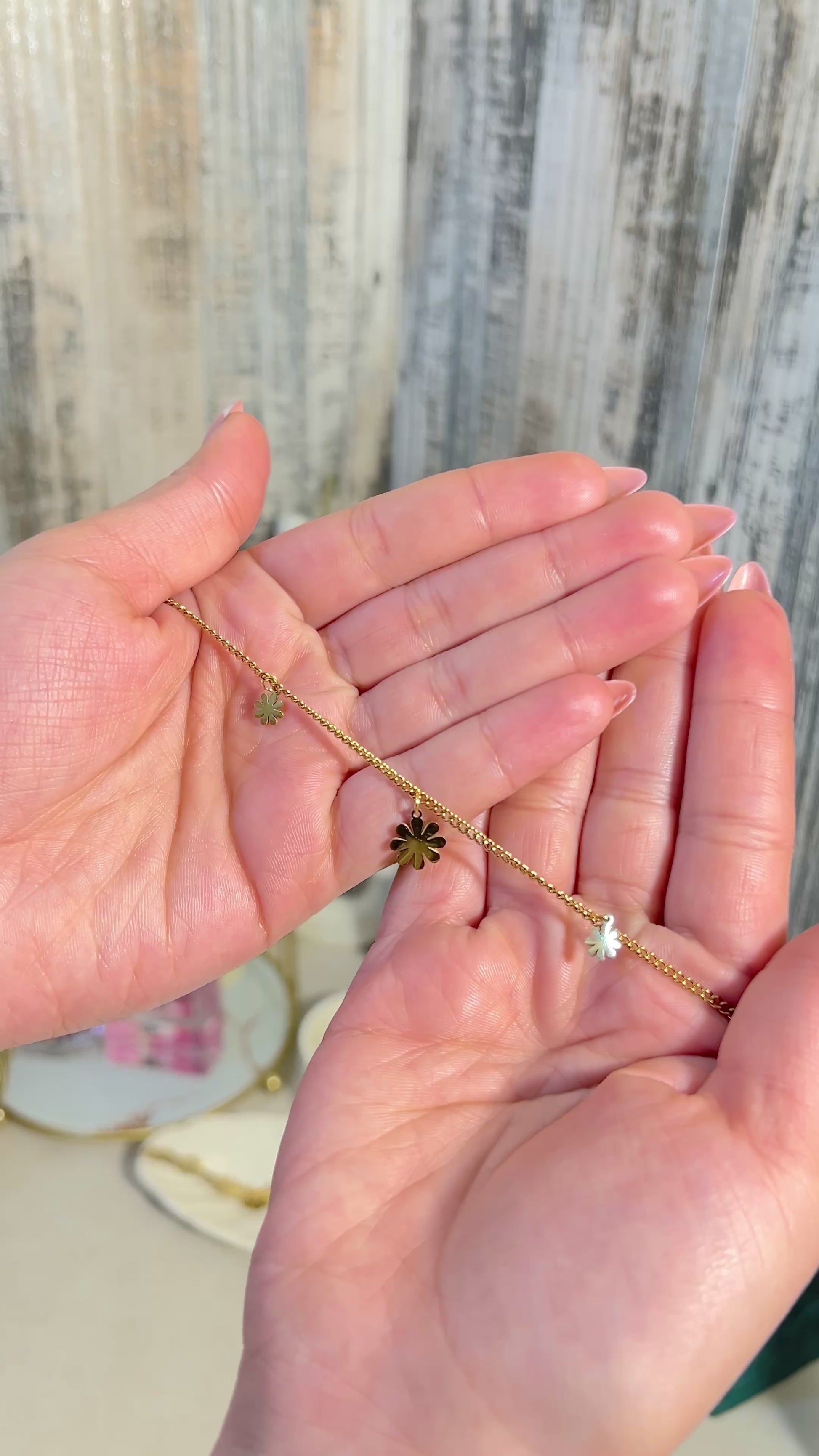 Waterproof Charm Bracelet - Delicate Gold Chain with Flower Charms held in hands, showcasing its elegance and charm.
